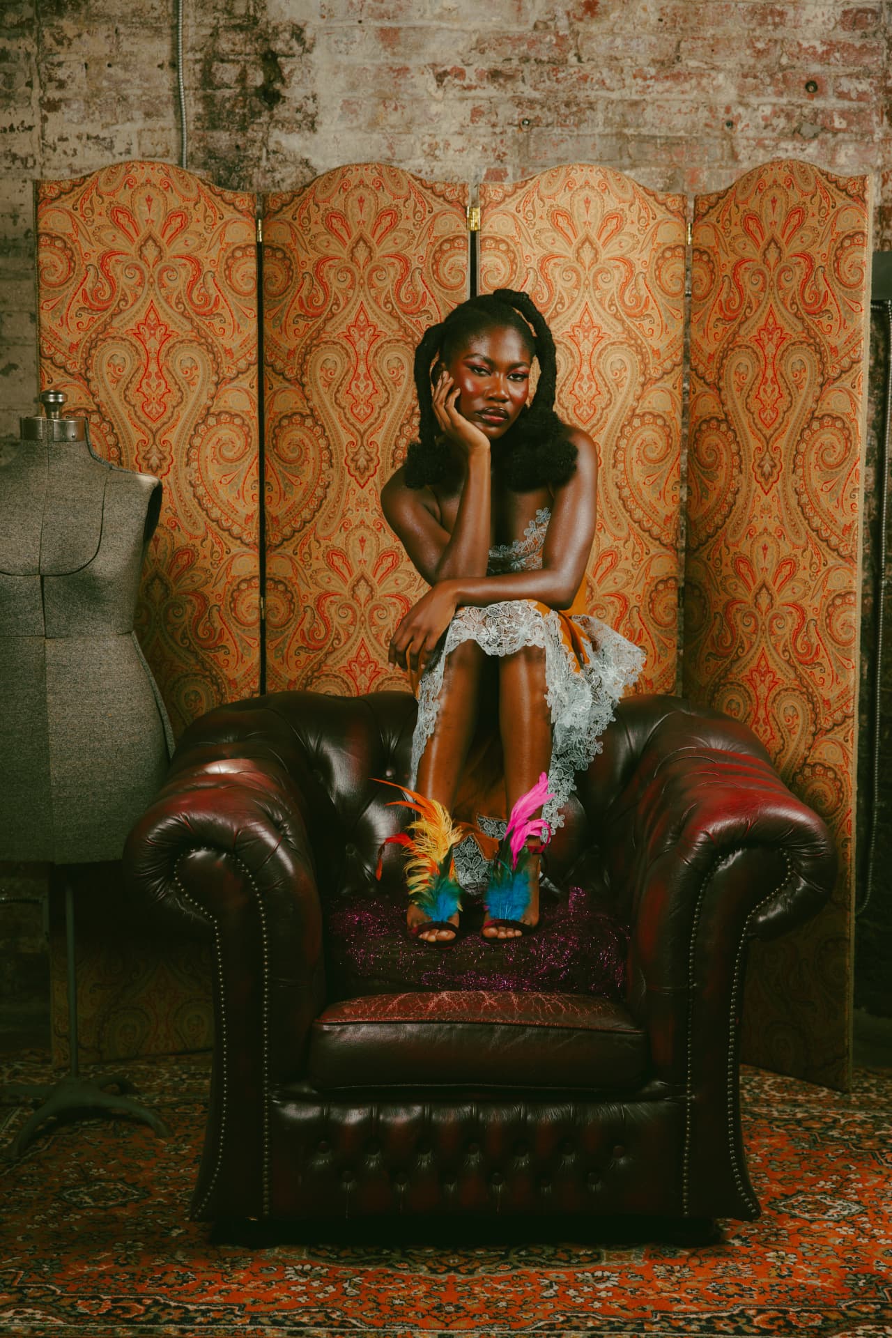 Model seated in a leather armchair wearing feathered TonyeFezēk heels