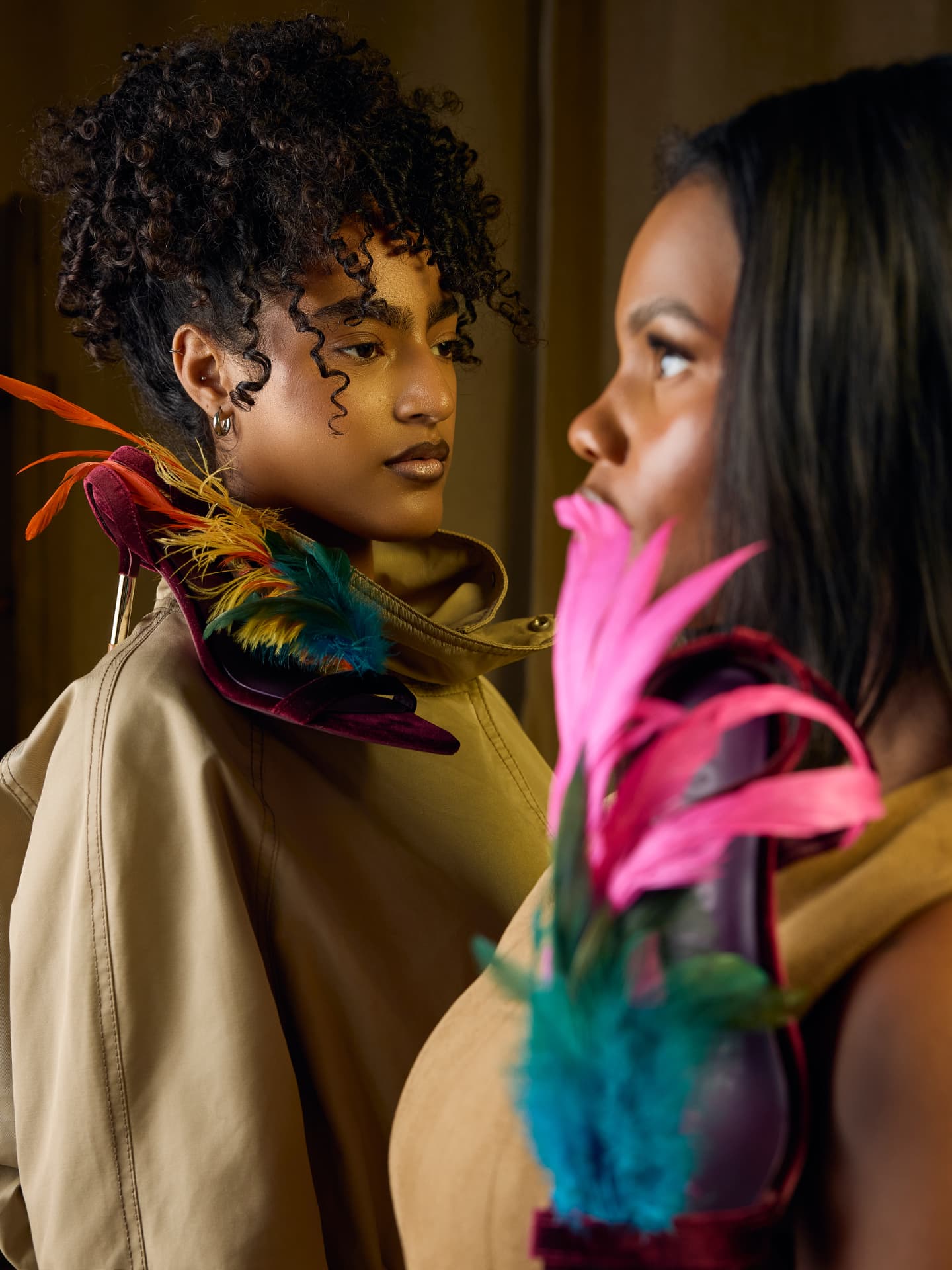 Two models mirrored, holding feathered TonyeFezēk heels